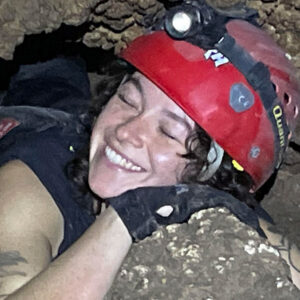 Laura Conway hugs a rock in a cave